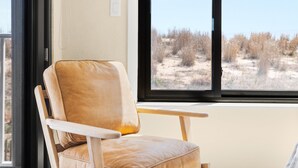 A room with a large window, a leather chair, and a view of a dry landscape. - Oceanfront Dunes Condo w/ Beach Views & Access (Ocean City)