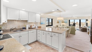 A spacious kitchen with white cabinets, a granite countertop, and a large island. - Oceanfront Dunes Condo w/ Beach Views & Access (Ocean City)