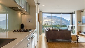 Una cocina moderna con estufa a gas, cafetera y vistas a las montañas a través de amplios ventanales.