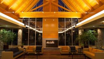 A spacious lobby with a high ceiling, wooden beams, a fireplace, and seating areas.