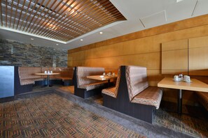 A restaurant with booth seating, a patterned carpet, and a wooden ceiling. - Edmonton Hotel & Convention Center (Edmonton)