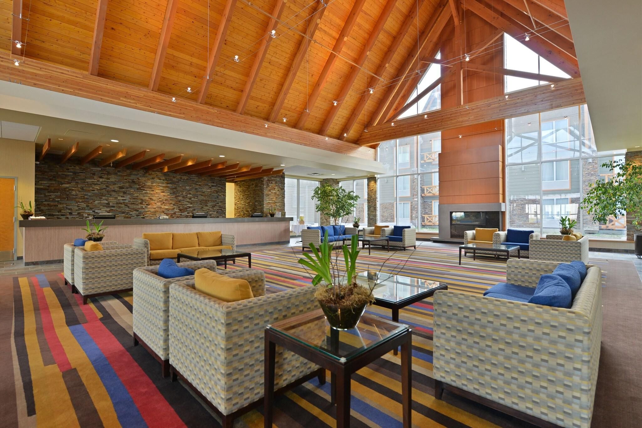 A spacious lobby with high ceilings, a stone wall, and multiple seating areas.
