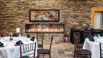Un restaurante con paredes de piedra, chimenea y mesas dispuestas para comer.