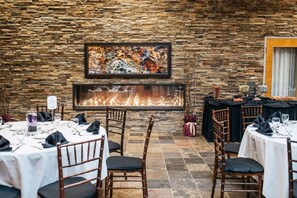 Un restaurante con paredes de piedra, chimenea y mesas dispuestas para comer.