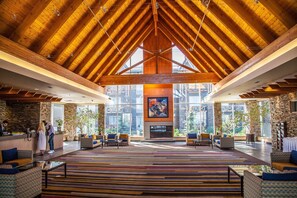 A spacious lobby with a high wooden ceiling, large windows, and a central fireplace. - Edmonton Hotel & Convention Center (Edmonton)