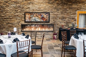 A restaurant with stone walls, a fireplace, and tables set for dining. - Edmonton Hotel & Convention Center (Edmonton)