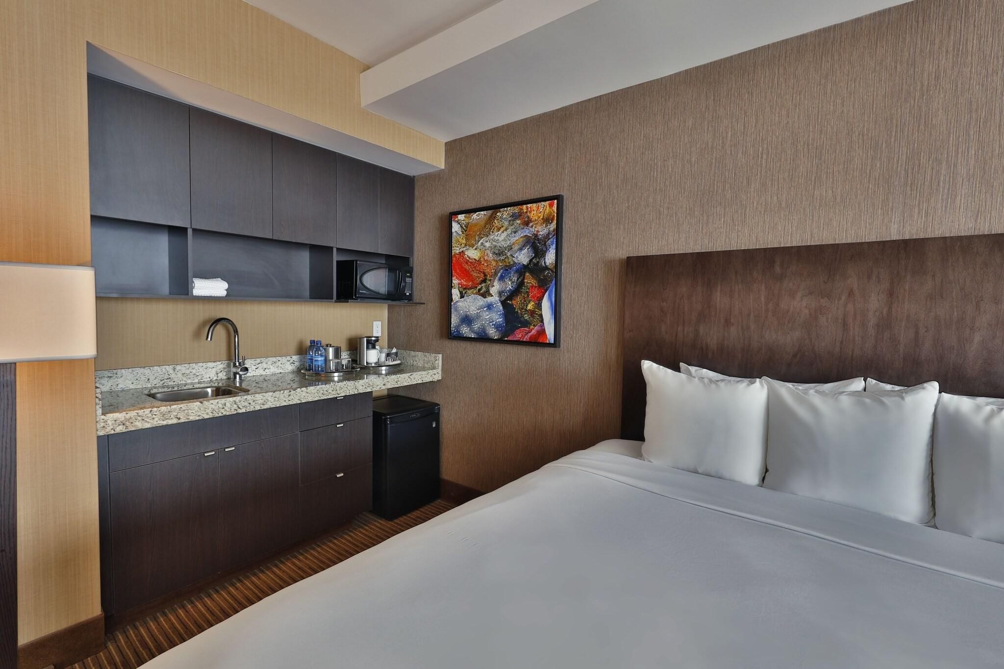Une chambre d’hôtel équipée d’un lit, d’un four à micro-ondes, d’un évier et d’un petit réfrigérateur.