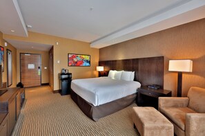A hotel room with a large bed, a desk, a chair, a nightstand, and a wall-mounted TV. - Edmonton Hotel & Convention Center (Edmonton)