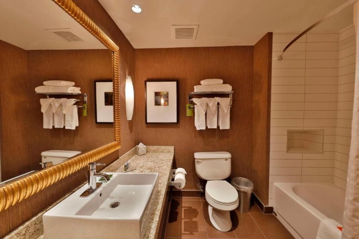 Une salle de bain moderne avec un grand miroir, un lavabo, des toilettes et une baignoire.