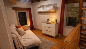 Ein Schlafzimmer mit einem Bett, einem Schminktisch, einem Fenster und einer Treppe.