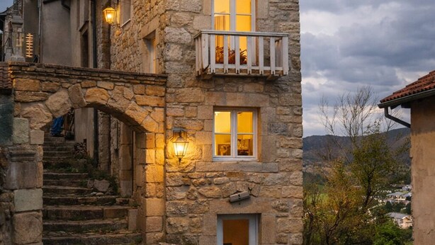Ein Steinhaus mit Balkon, einer Treppe zum Eingang und einer Tür mit einer kleinen Veranda.