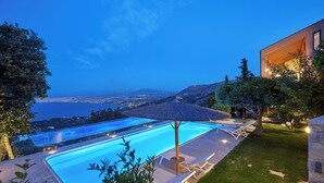 A swimming pool with lounge chairs and an umbrella, surrounded by greenery and a view of the sea. - Villa Vollard  | 5 Bedrooms with Private Pool Jacuzzi and Panoramic Sea View (Heraklion)