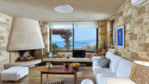 A living room with a stone wall, a fireplace, a sofa, a coffee table, and a television. - Villa Vollard  | 5 Bedrooms with Private Pool Jacuzzi and Panoramic Sea View (Heraklion)