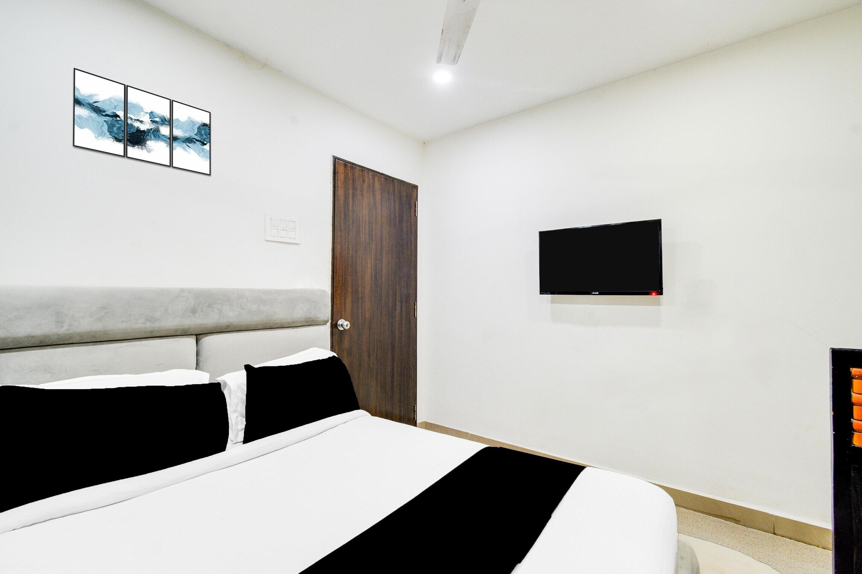 A bedroom with a bed, a TV mounted on the wall, and a door.