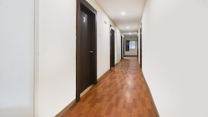 A long, narrow hallway with wooden flooring and dark doors on one side. - Townhouse Hitec City Metro Station (Hyderabad)