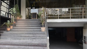 A set of outdoor stairs leading to a building entrance with potted plants and a metal railing. - Townhouse Hitec City Metro Station (Hyderabad)