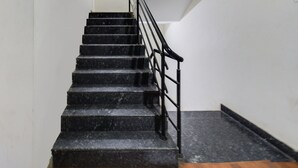 A staircase with black steps and a metal railing. - Townhouse Hitec City Metro Station (Hyderabad)