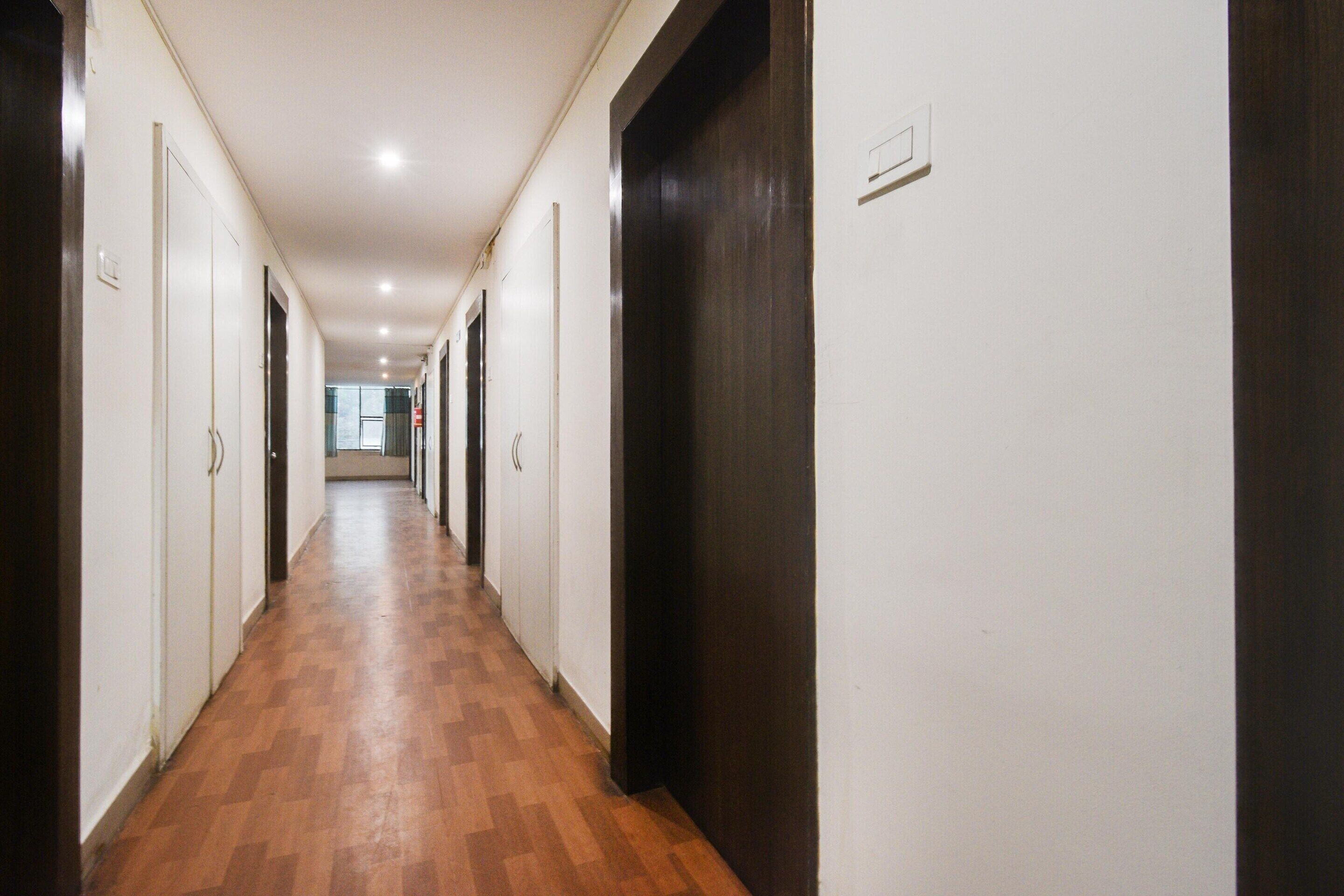 Un long couloir étroit, doté d’un plancher en bois, de murs blancs et de portes en bois foncé.