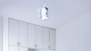 Un dormitorio con cama, armario, mesita de noche y lámpara colgante.