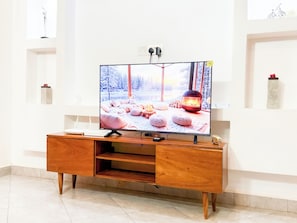 A television on a wooden stand with a winter scene on the screen. - Constatia Homes  (Kampala)