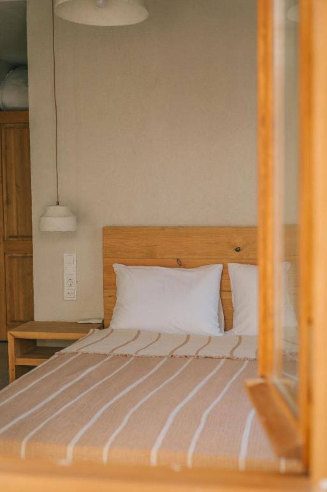 A bed with a striped blanket, a wooden headboard, and a white pillow.