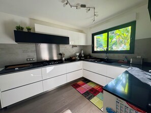 Eine moderne Küche mit weißen Schränken, einer Edelstahl-Dunstabzugshaube, einer schwarzen Arbeitsplatte und einem farbenfrohen Teppich.