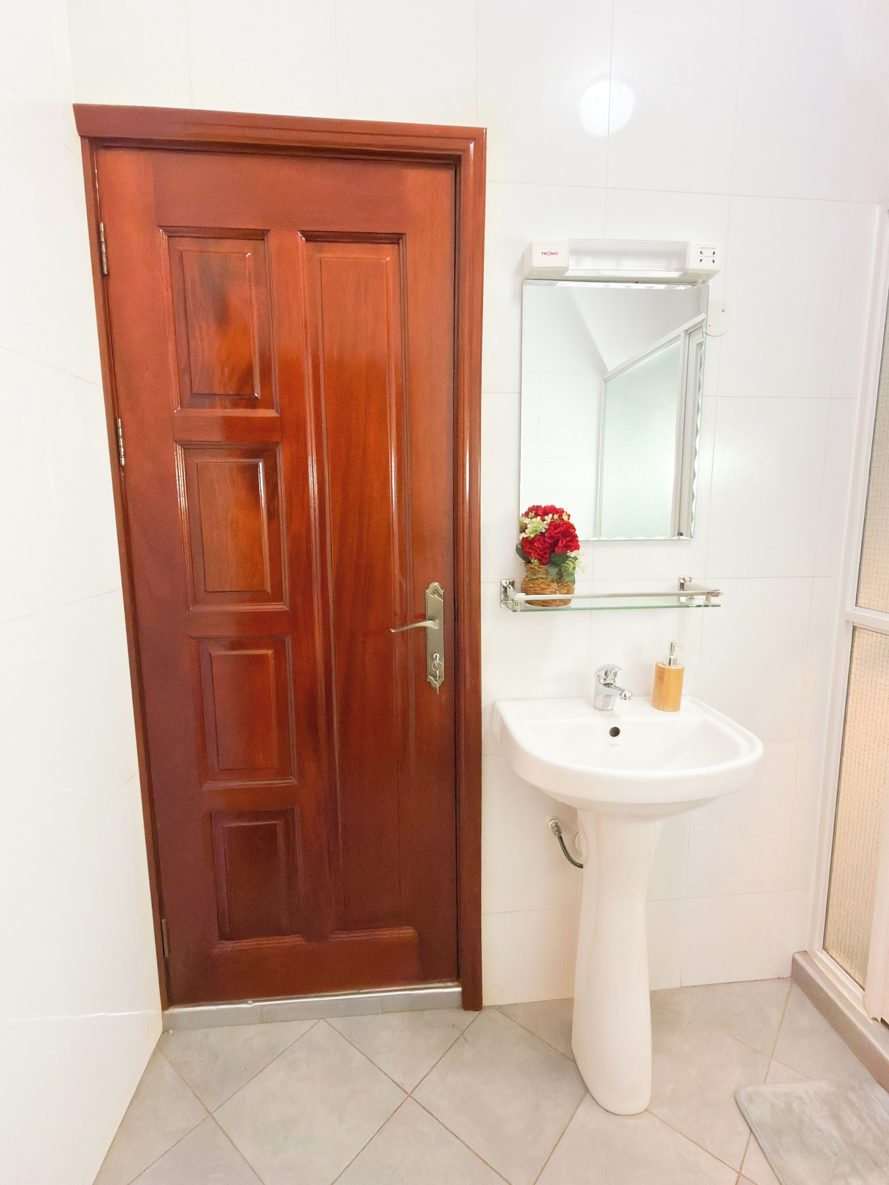Una puerta de madera, un lavamanos blanco y un espejo en un baño.