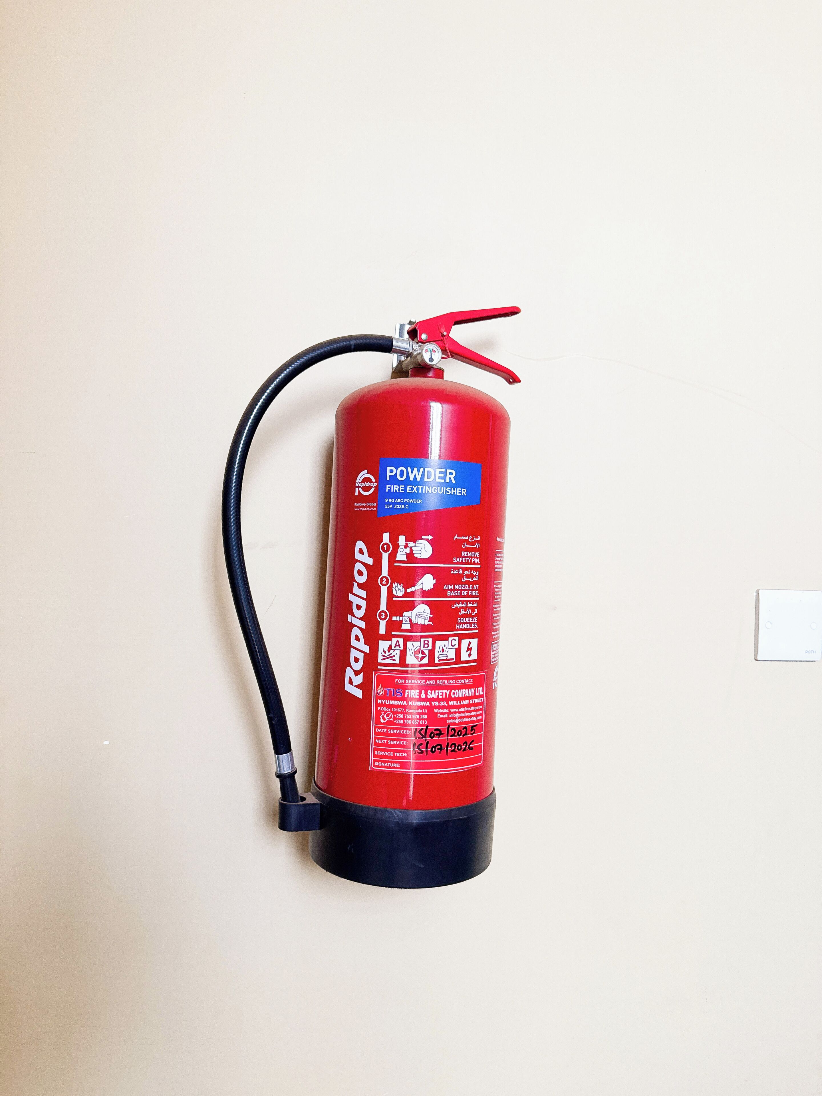 Extintor de polvo rojo montado en la pared.