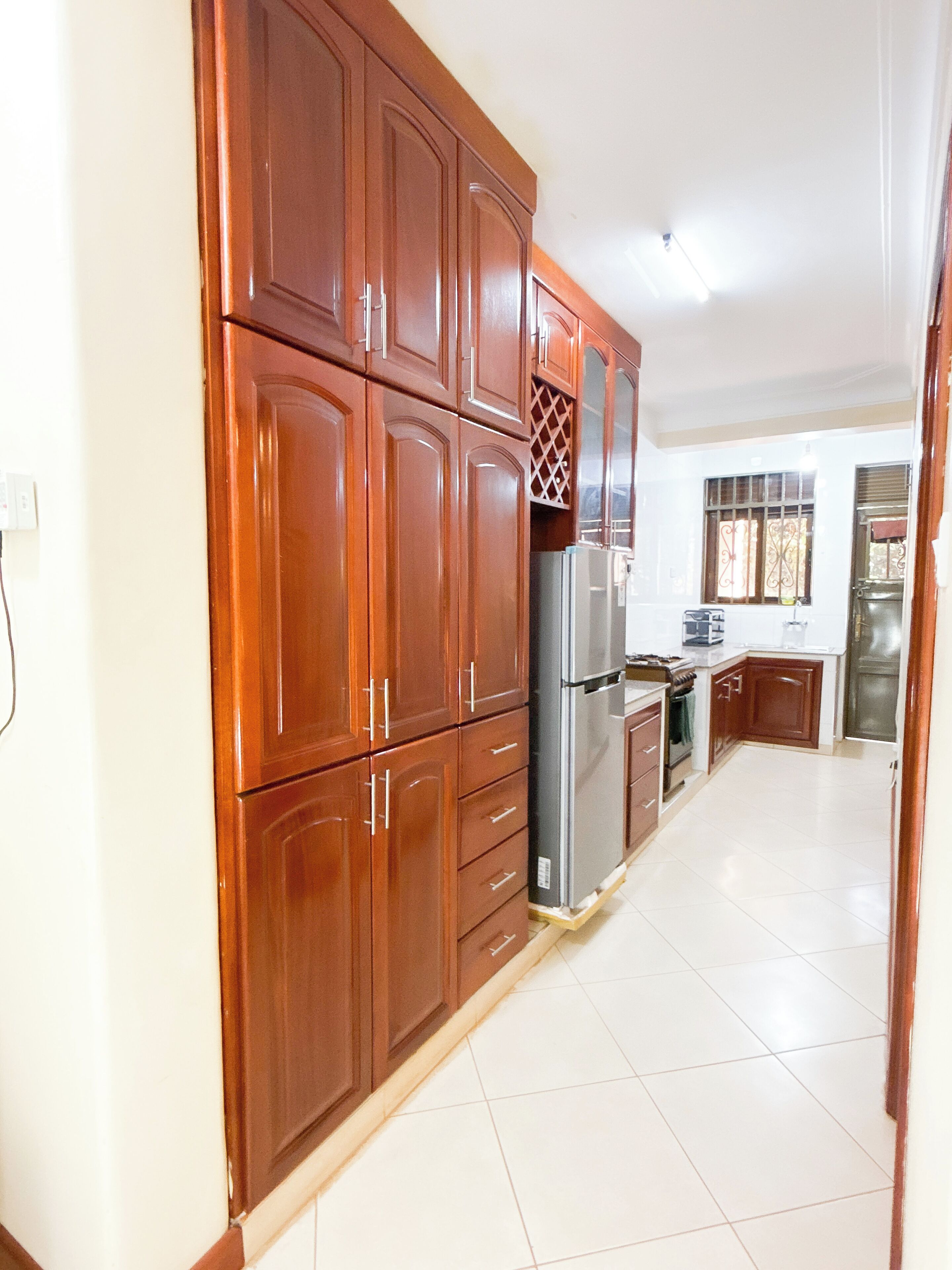 A kitchen with wooden cabinets, a stainless steel refrigerator, and a tiled floor.