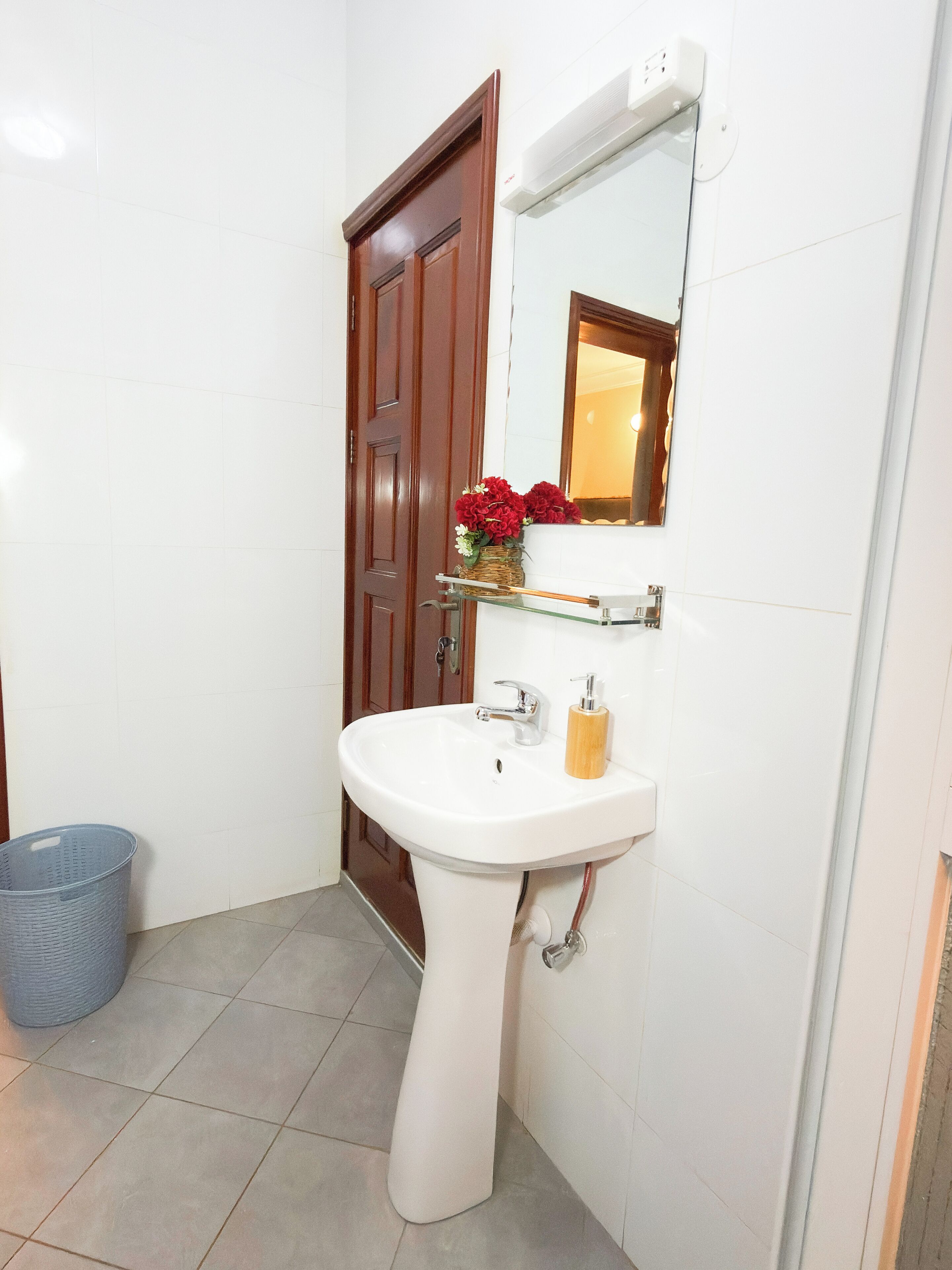 Un baño con un lavabo blanco, puerta de madera y un espejo.