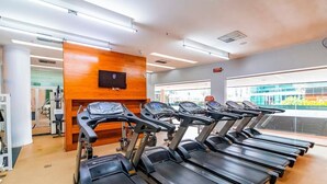Une salle de sport équipée de tapis de course, avec un mur en bois et une grande fenêtre.