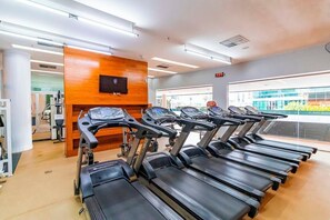 Une salle de sport équipée de tapis de course, avec un mur en bois et une grande fenêtre.