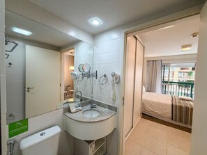 Un baño de hotel con lavamanos, espejo y secador de pelo.