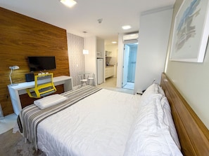 Ein Hotelzimmer mit Bett, Schreibtisch, Stuhl, Fernseher und einem durch eine offene Tür einsehbaren Badezimmer.