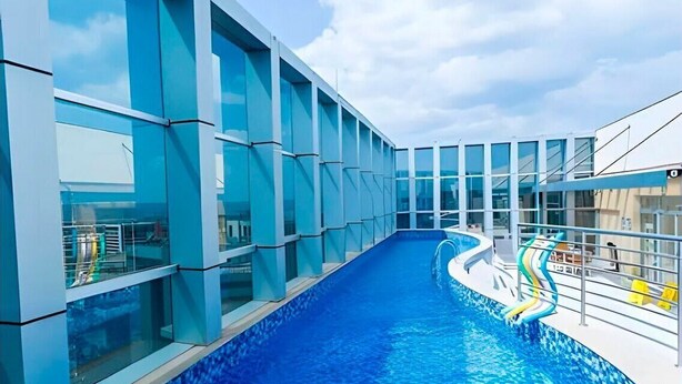 Ein moderner, überdachter Pool mit Glaswänden und klarem, blauem Wasser.