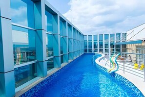 Une piscine intérieure moderne, dotée de parois en verre et d’une eau d’un bleu cristallin.