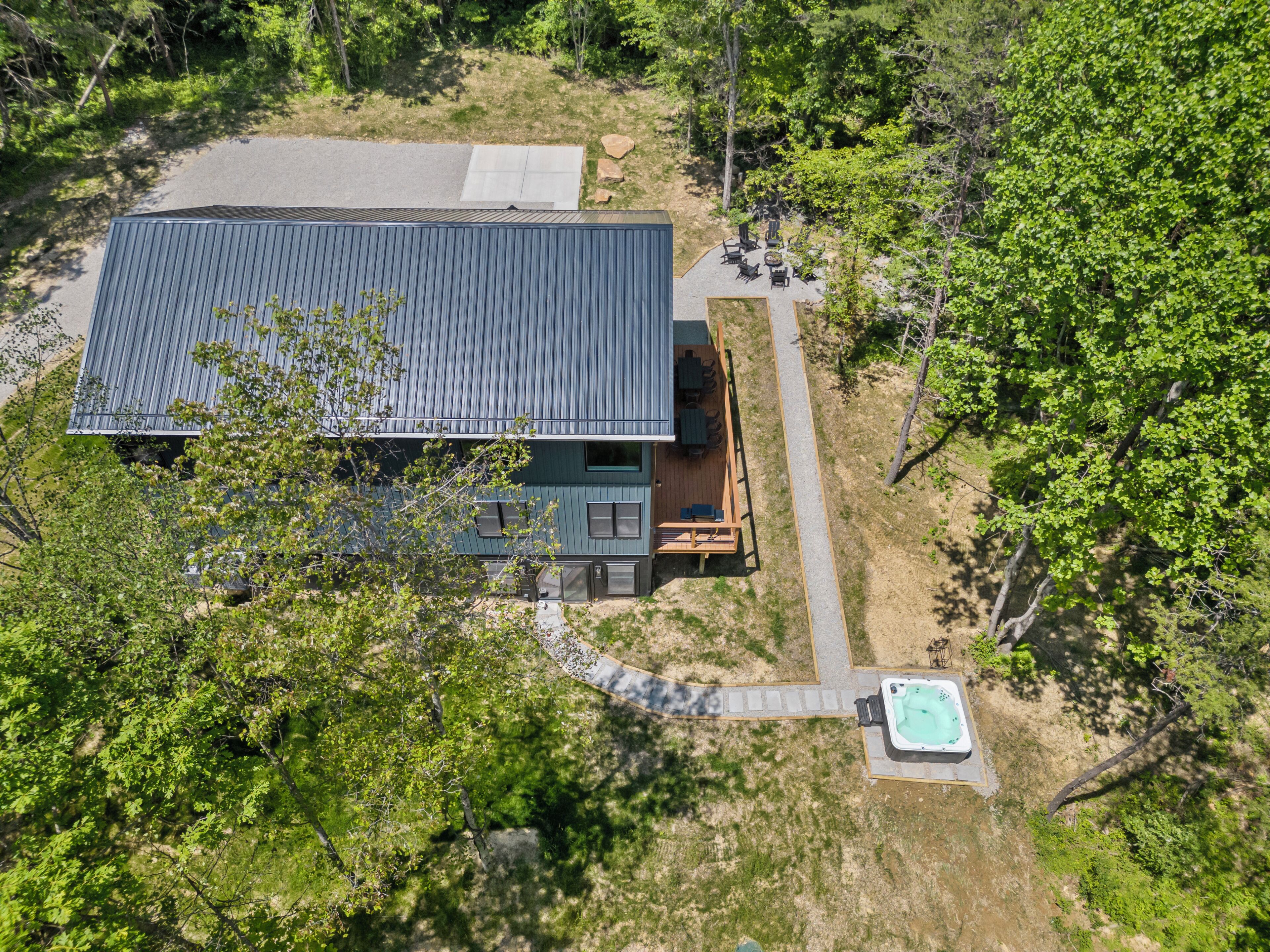 Une maison dotée d’une grande terrasse, d’un jacuzzi et d’une allée pavée.