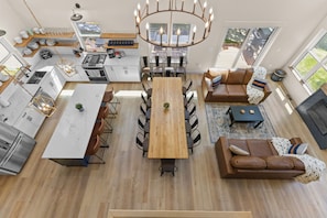 Une cuisine moderne dotée d’un îlot central, d’un coin repas avec une table en bois et d’un espace salon confortable avec un canapé marron.