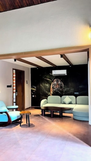 Ein modernes Wohnzimmer mit einer Couch, einem Couchtisch und einem Sessel. An der Wand ist ein Wandbild von einem Tiger zu sehen.
