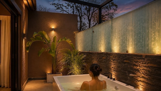 Un espace de bien-être comprenant une baignoire, des plantes en pot et un mur à motifs.