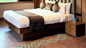 Une chambre moderne avec un grand lit, un ventilateur de plafond, des lampes suspendues, une fenêtre avec vue et un panneau décoratif mural.