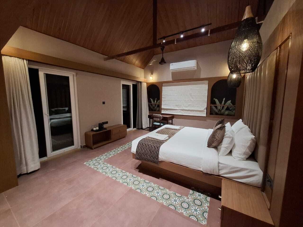 Un dormitorio con cama, escritorio, silla, ventana y vistas al exterior.