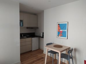 A compact kitchen with a dining area, featuring a microwave, stove, and cabinets.