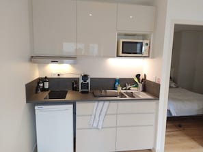 Eine kleine Küchenzeile mit Mikrowelle, Kaffeemaschine und kleinem Kühlschrank.