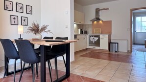 Uma cozinha moderna com fogão, forno e uma área de jantar com cadeiras e mesa.