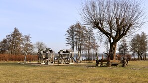 Ein Spielplatz mit Rutsche und Klettergerüsten, umgeben von Bäumen und einer Bank.