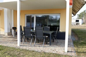 An outdoor patio with a table and chairs, a sliding glass door, and a brick floor. - Seeluft vacation home with lake view in Warin for a relaxing vacation (Warin)