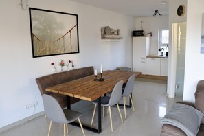A dining area with a wooden table, grey chairs, a brown sofa, and a kitchen in the background. - Seeluft vacation home with lake view in Warin for a relaxing vacation (Warin)