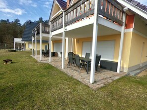 A two-story building with a covered patio area, outdoor seating, and a garage. - Seeluft vacation home with lake view in Warin for a relaxing vacation (Warin)