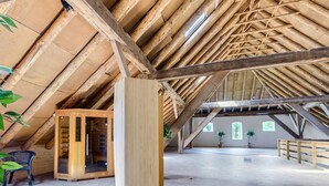 Ein Dachzimmer mit schrägem Holzboden, einem Holzkasten und einem Stuhl.